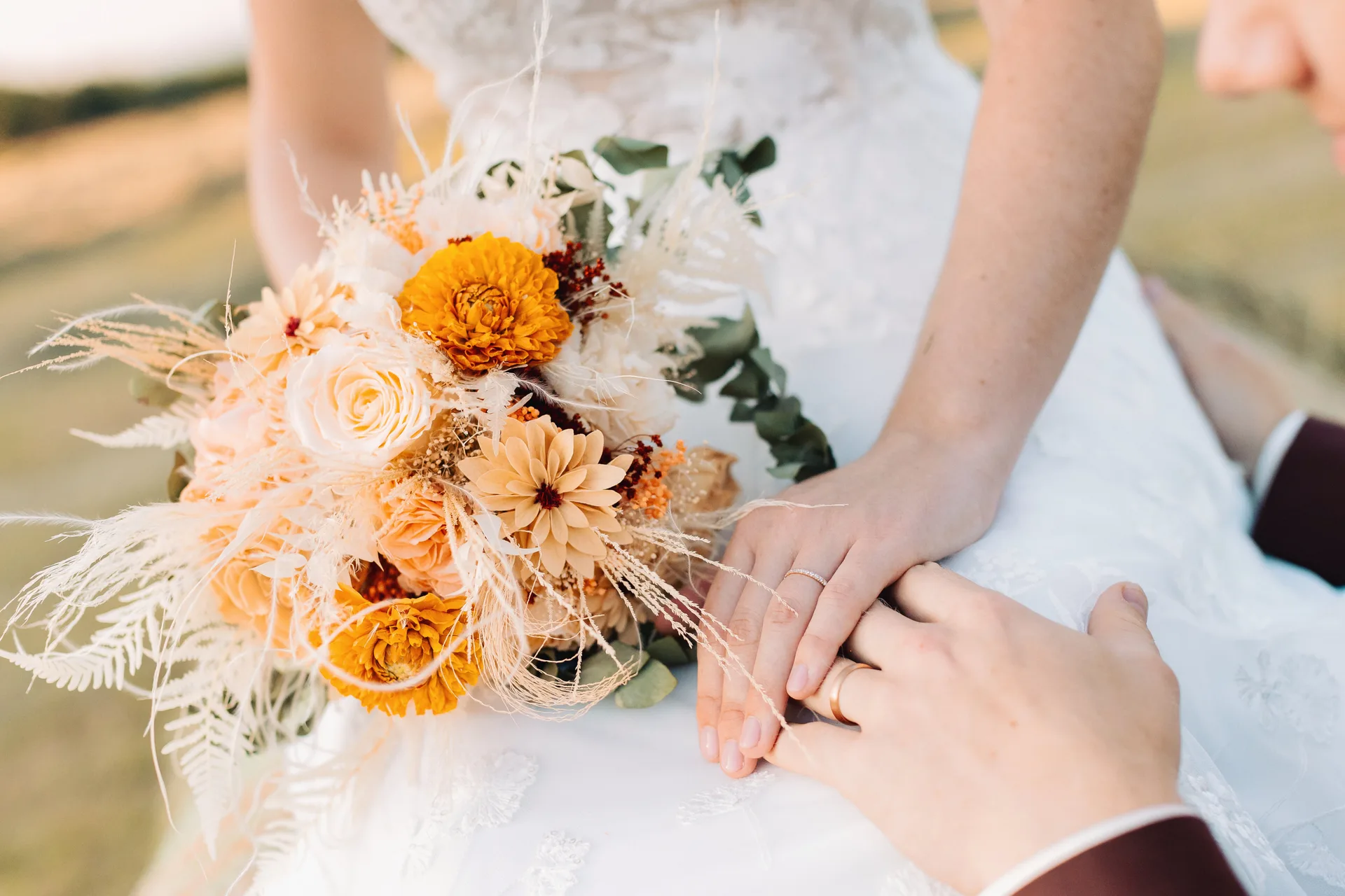 Bouquet de mariée orange et blanc, mains des mariés et alliances