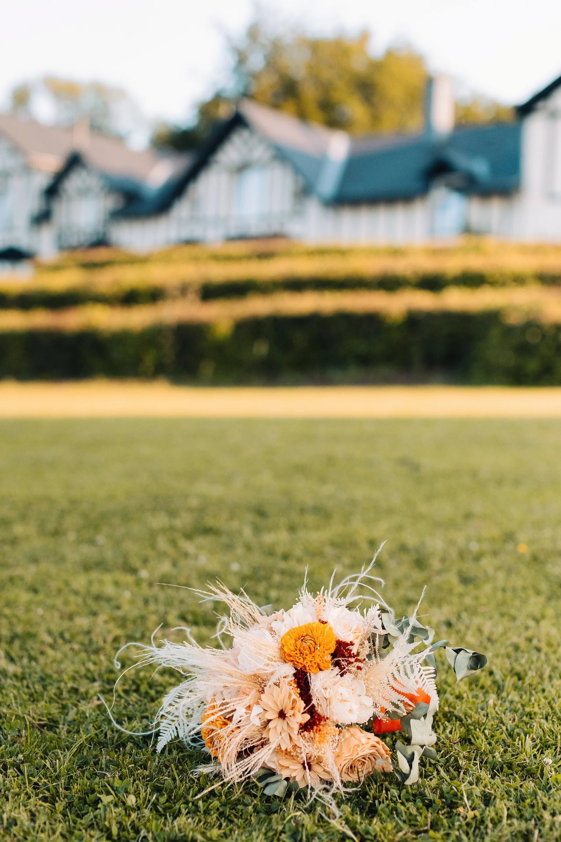 Bouquet de mariée posé dans l'herbe devant le Domaine de Bronromme