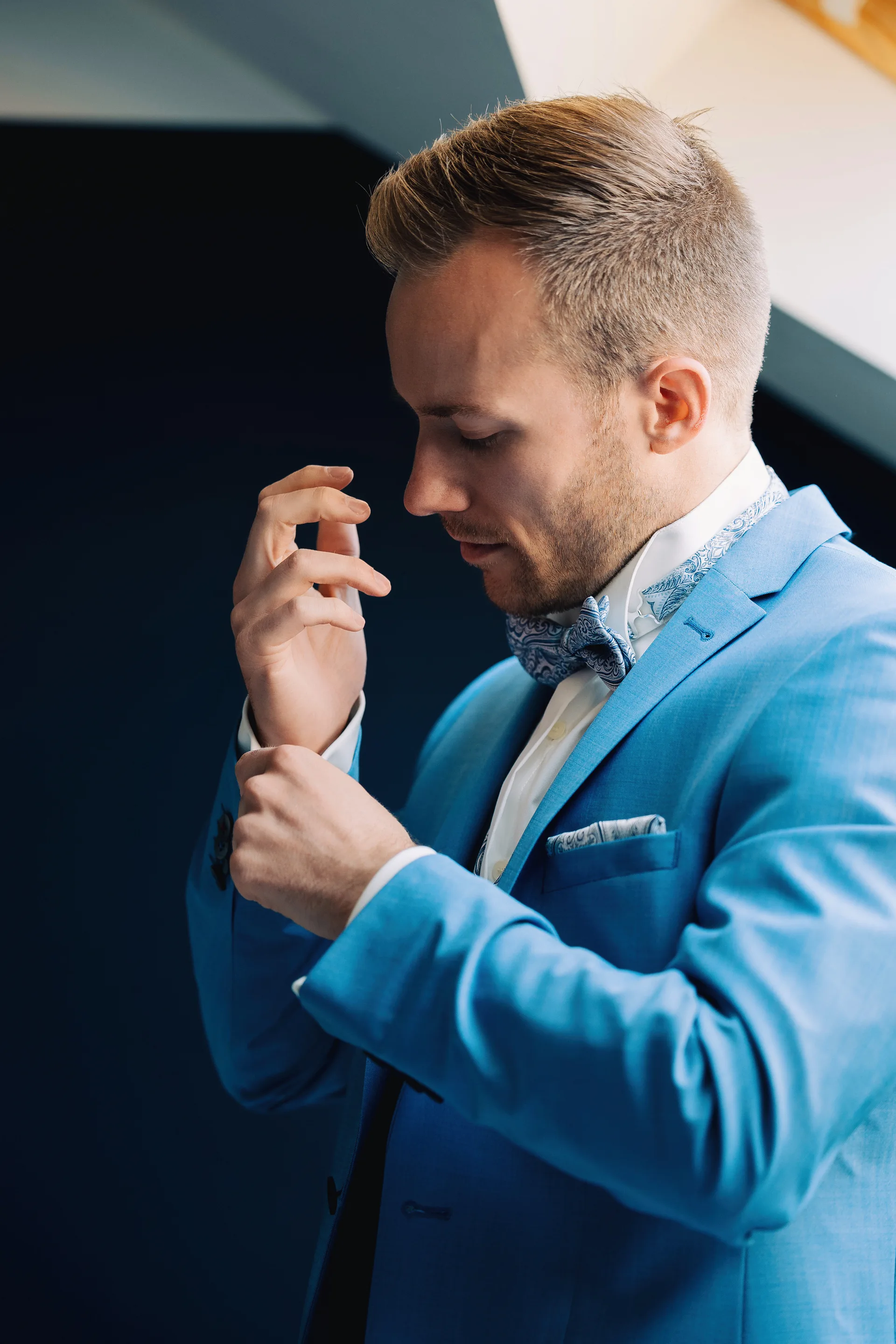 Le marié ajuste sa tenue avant la cérémonie, costume bleu