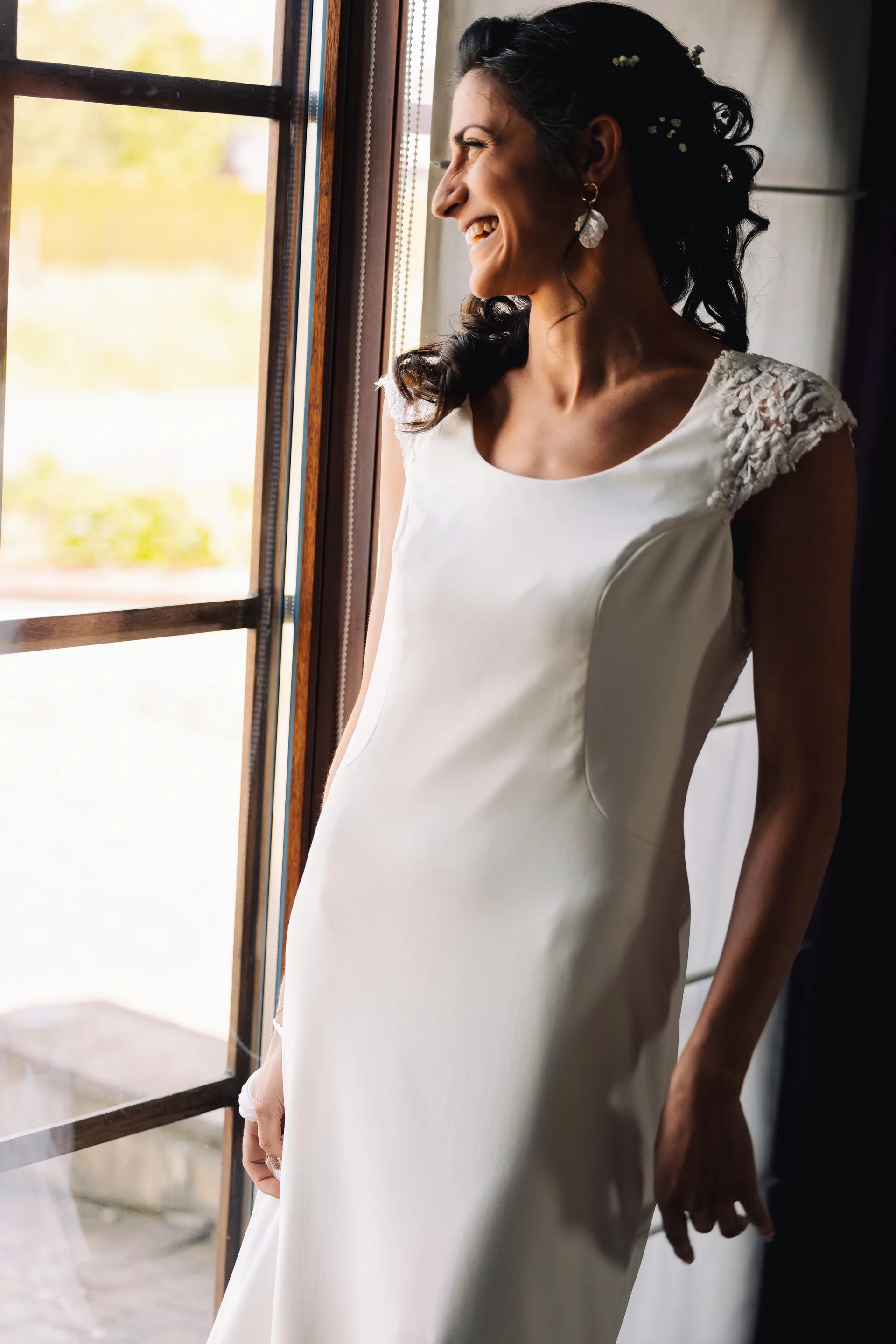 La mariée souriante devant la fenêtre, juste avant la cérémonie