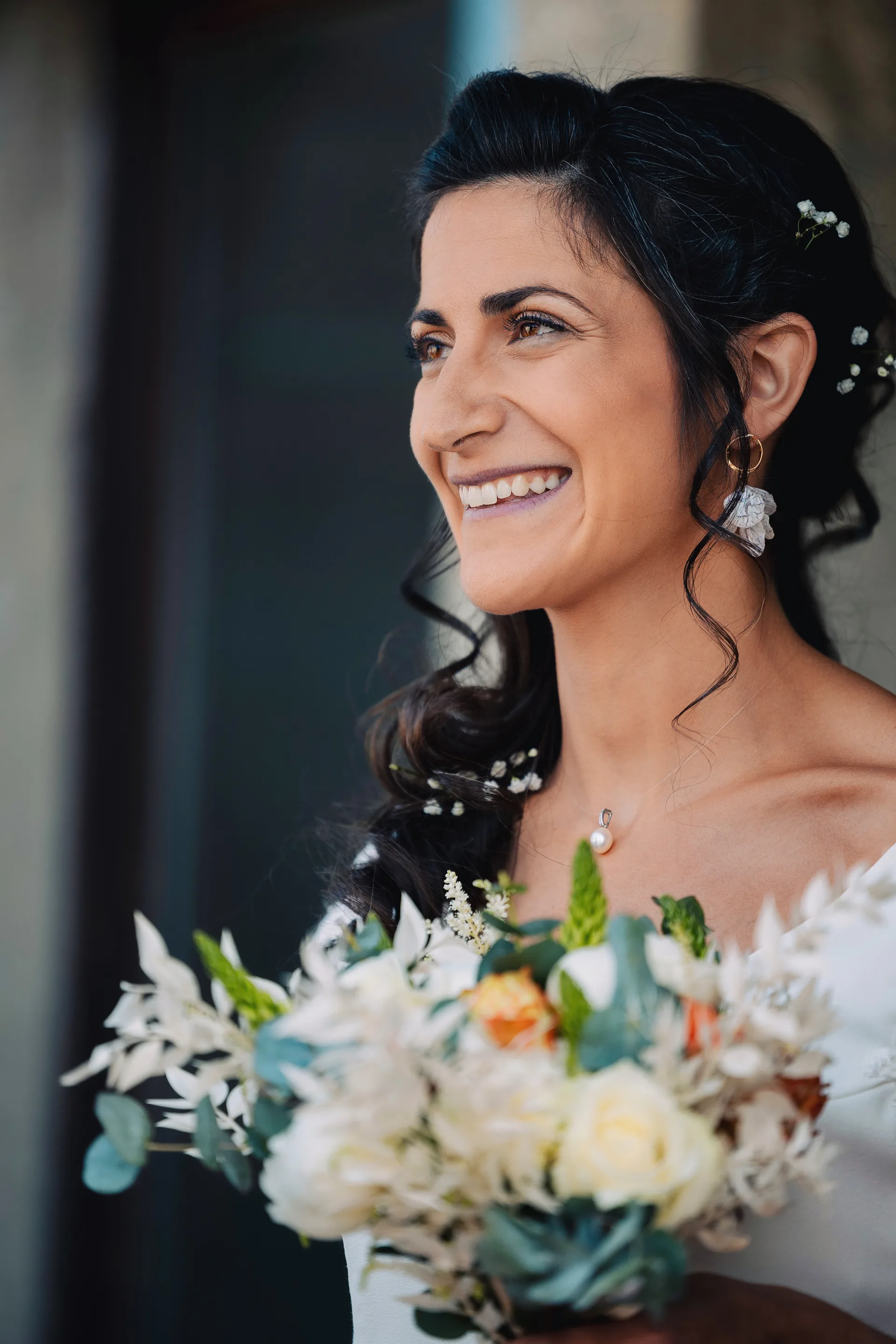 Portrait rapproché de la mariée et son bouquet, regard rieur